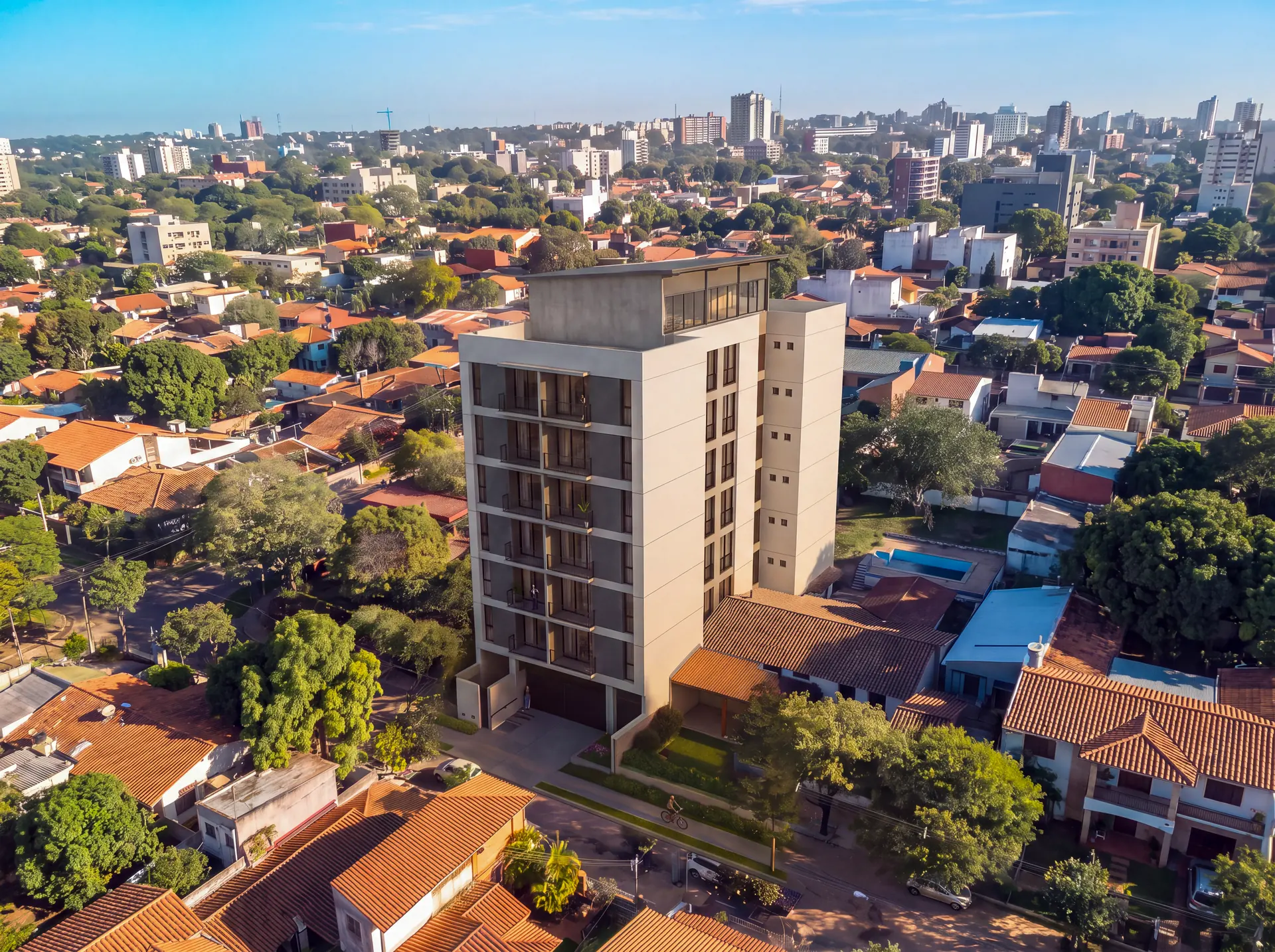 Render aéreo del edificio Barrio Jara entre las casas bajas y el arbolado de un barrio residencial de Asunción
